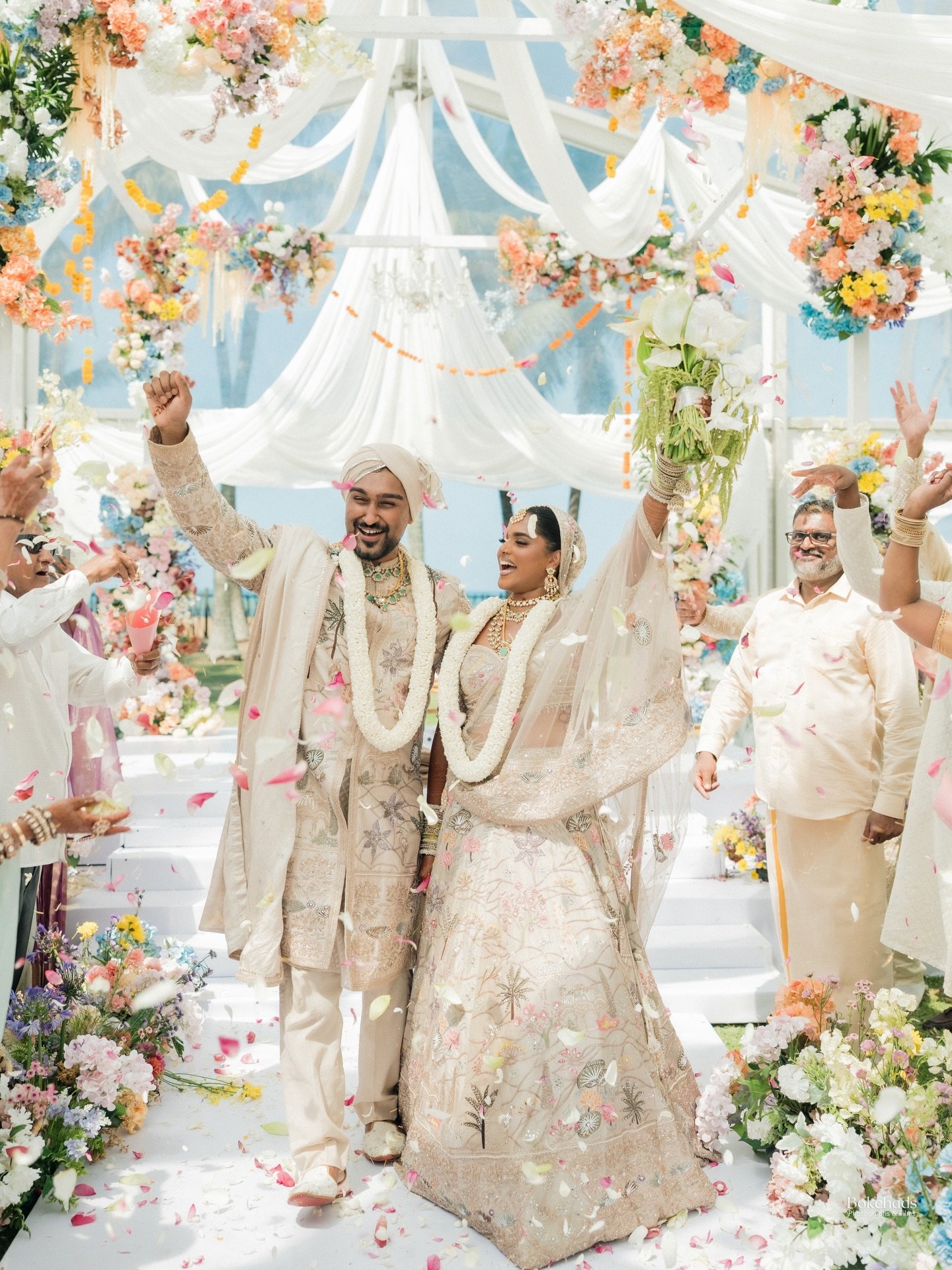 A newlywed couple celebrating beneath a floral wedding canopy